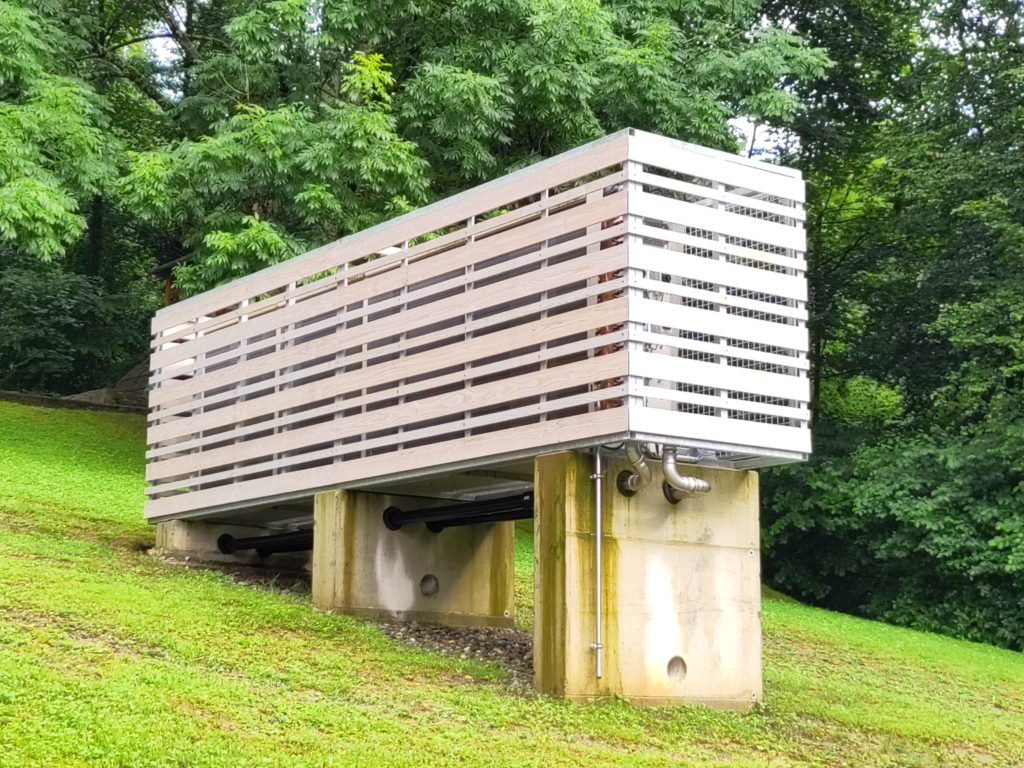 freistehender Luftwärmetauscher, mit Holzlatten als Sichtschutz.